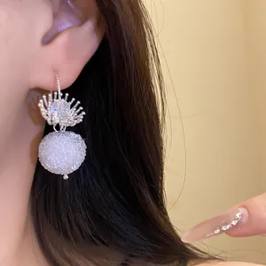 Detail of elegant silver earring with crystal flower and white textured round pendant