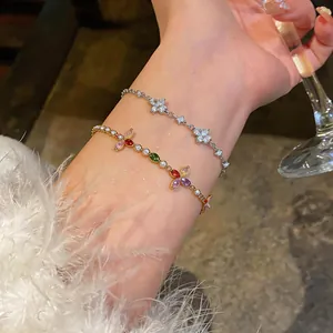 Dettaglio di braccialetti scintillanti in zirconia con fiori colorati e bianchi al polso