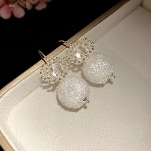 Detailed close-up of crystal flower dangle earrings with textured round bead pendants