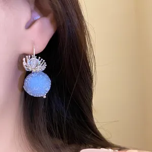 Close-up detail shot of a blue crystal ball earring with silver floral cap on ear