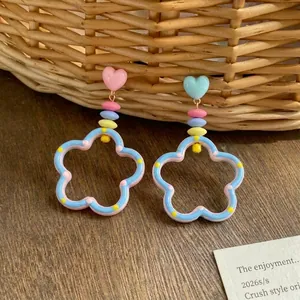 Macro view of colorful dopamine hollow flower earrings featuring sweet pink heart studs
