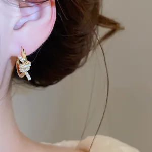 Close-up of 14k gold plated knot hoop earrings with sparkling cubic zirconia on ear