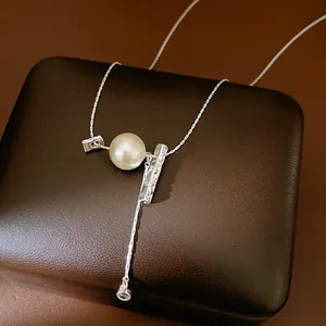 Close-up of a silver Y-necklace with textured bar and pearl on a brown leather box