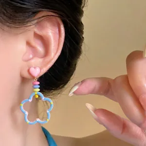 Close-up of vibrant dopamine style hollow flower earrings with pink heart charm