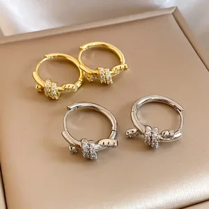Detail showing 14k gold and silver plated knot hoop earrings with pavé zircons.