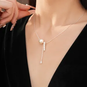 Close-up of elegant silver zircon necklace with pearl and bar drop on model's neck