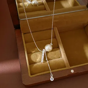 High-quality close-up of a silver lariat necklace featuring a pearl and textured bar pendant