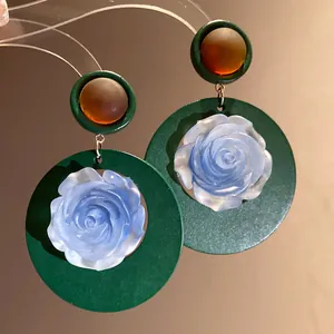 Dettaglio di orecchini vintage verdi con una delicata rosa in resina blu satinata opaca