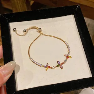 Primo piano di un bracciale dorato con fiori in zircone colorato e chiusura regolabile scorrevole