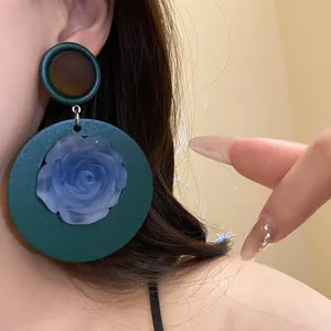 Dettaglio di orecchini vintage in resina con ciondolo a rosa blu e cornice verde