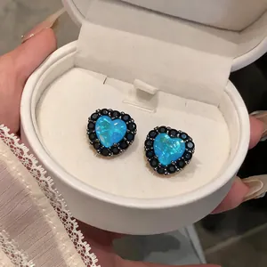 Nahaufnahme von herzförmigen Ohrsteckern mit blauem Opal und schwarzem Zirkonia in Geschenkbox