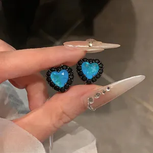 Nahaufnahme von blauen herzförmigen Ohrsteckern mit einem schwarzen Zirkonia-Rand