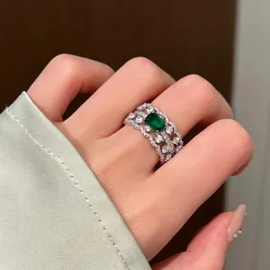 Detailed view of vintage hollow ring with emerald green stone on model finger.