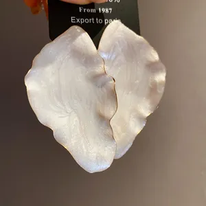 Close-up detail of vintage white iridescent leaf earrings with elegant gold edges