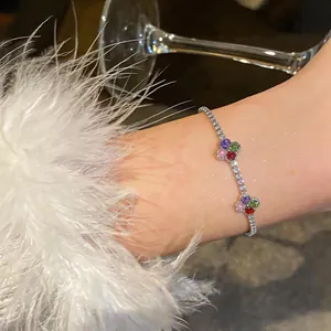 Dettaglio di un braccialetto di fiori in zircone colorato sul polso con manica in piuma