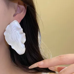 Close-up detail of vintage iridescent white leaf-shaped earrings on a model's ear