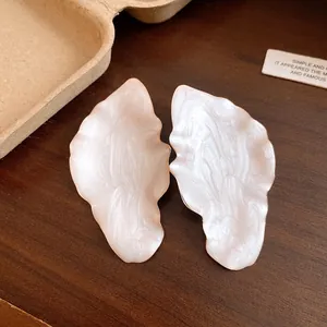 Close-up view of vintage cream dripping oil leaf-shaped metal stud earrings with glossy finish