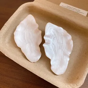 Close-up detail of vintage leaf stud earrings with a pearlescent cream enamel finish