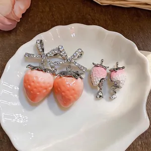 Detail of sweet resin strawberry earrings featuring zircon bow and crystal drop charms