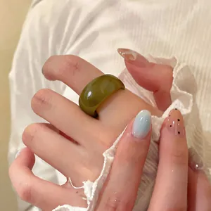 Détail d'une bague ovale en résine vert olive vintage sur une main avec nail art