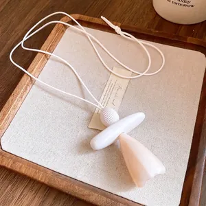 Elegant minimalist resin pendant necklace with white leather cord on a wooden tray