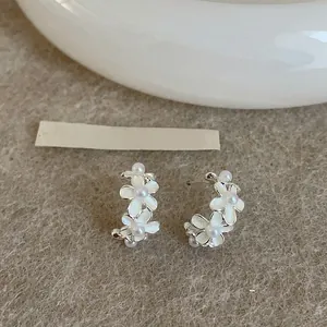 Dettaglio orecchini a lobo a forma di C con fiori, perle bianche e perni in argento