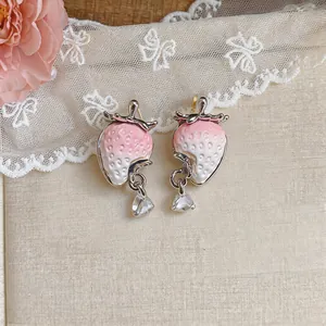Close-up of pink resin strawberry earrings with sparkling zircon waterdrop pendants.