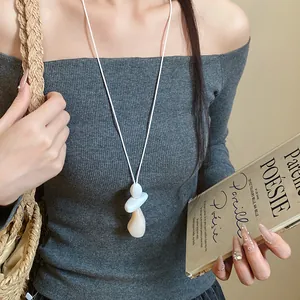 Minimalist resin pendant necklace with white cord worn by a model in lifestyle setting