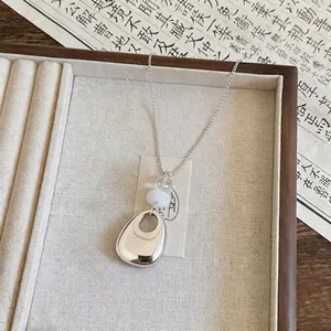 Minimalist silver teardrop pendant necklace with white and clear beads on jewelry tray