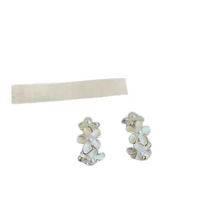 Eleganti orecchini a fiore in smalto bianco a forma di C con perle su sfondo bianco