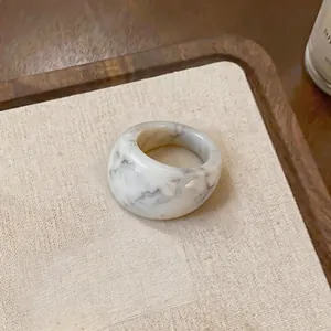 Gros plan d'une bague en résine épaisse affichant un motif de pierre marbrée élégant