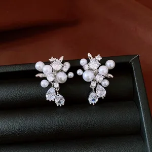 Close-up of elegant silver stud earrings with white pearls and clear teardrop zircons