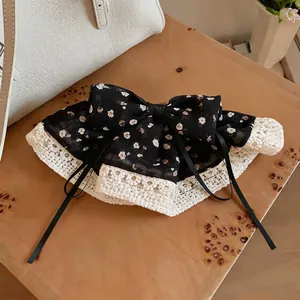 Gedetailleerd overzicht van een zwarte bloemen haarstrik met witte kanten rand.