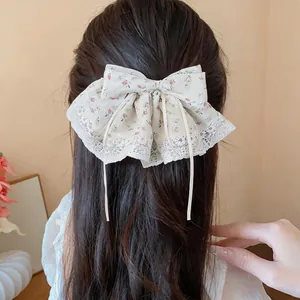 Detail van elegante bloemenstof strik haarklem met kantrand gedragen op bruin haar