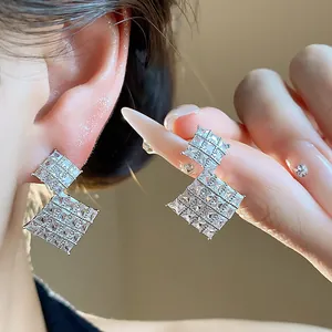 Dettaglio di orecchini a rombo in argento con grappoli di zirconi quadrati lucidi.