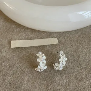 Dettaglio dei raffinati orecchini a cerchio a C con fiori in smalto bianco e perle.