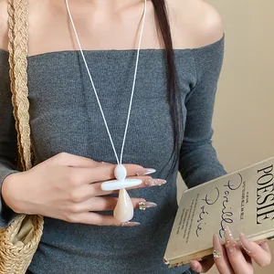 Detail shot of a minimalist resin pendant necklace featuring a stylish white leather cord.