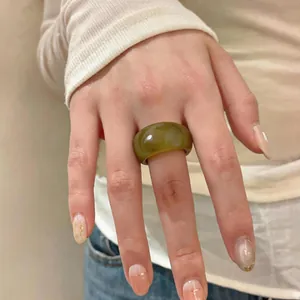 Gros plan d'une bague épaisse en résine vert olive marbrée de style vintage au doigt