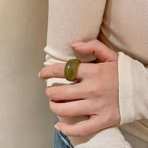 Grosse bague en résine vert mousse avec une finition brillante portée par le modèle.