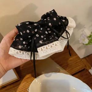 Detail van een zwarte bloemen haarstrik van stof met een delicate crème kantafwerking