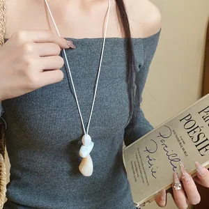 Close-up of minimalist resin pendant necklace with white leather cord worn by model