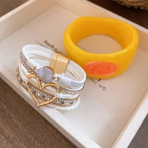 Detailed view of white layered heart bracelet and elegant yellow resin bangle in a tray