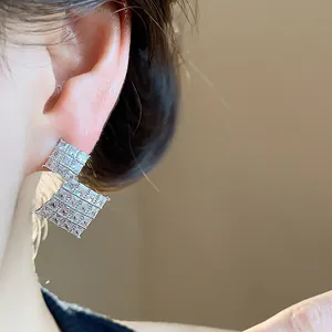 Dettaglio orecchini a lobo a forma di rombo color argento con zirconi brillanti