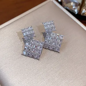 Primo piano di eleganti orecchini a lobo quadrati in zirconia su un portagioie di lusso