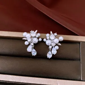 Macro view of silver needle zircon and pearl drop earrings in a jewelry box