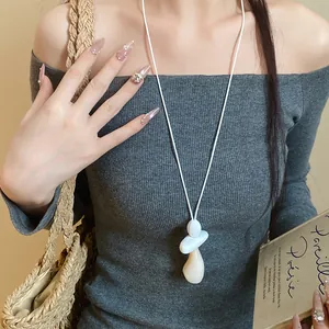 Close-up of minimalist resin pendant necklace worn with a grey knit top
