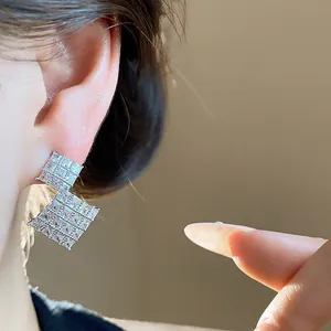 Primo piano dettagliato di orecchini geometrici a rombo con zirconi scintillanti.