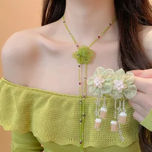 Detail of green beaded flower necklace and matching tassel earrings worn by model