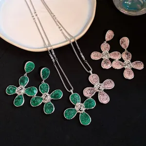 Close-up of elegant resin wrinkled flower necklace and earrings in green and pink