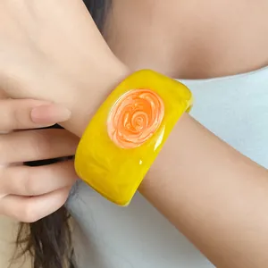 Close-up of yellow resin bangle featuring a vibrant orange swirl drip oil center